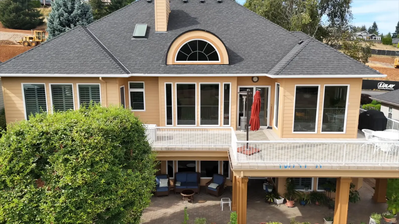 Rear of the same golf course home repainted warm sand with bronze trim and white deck rails