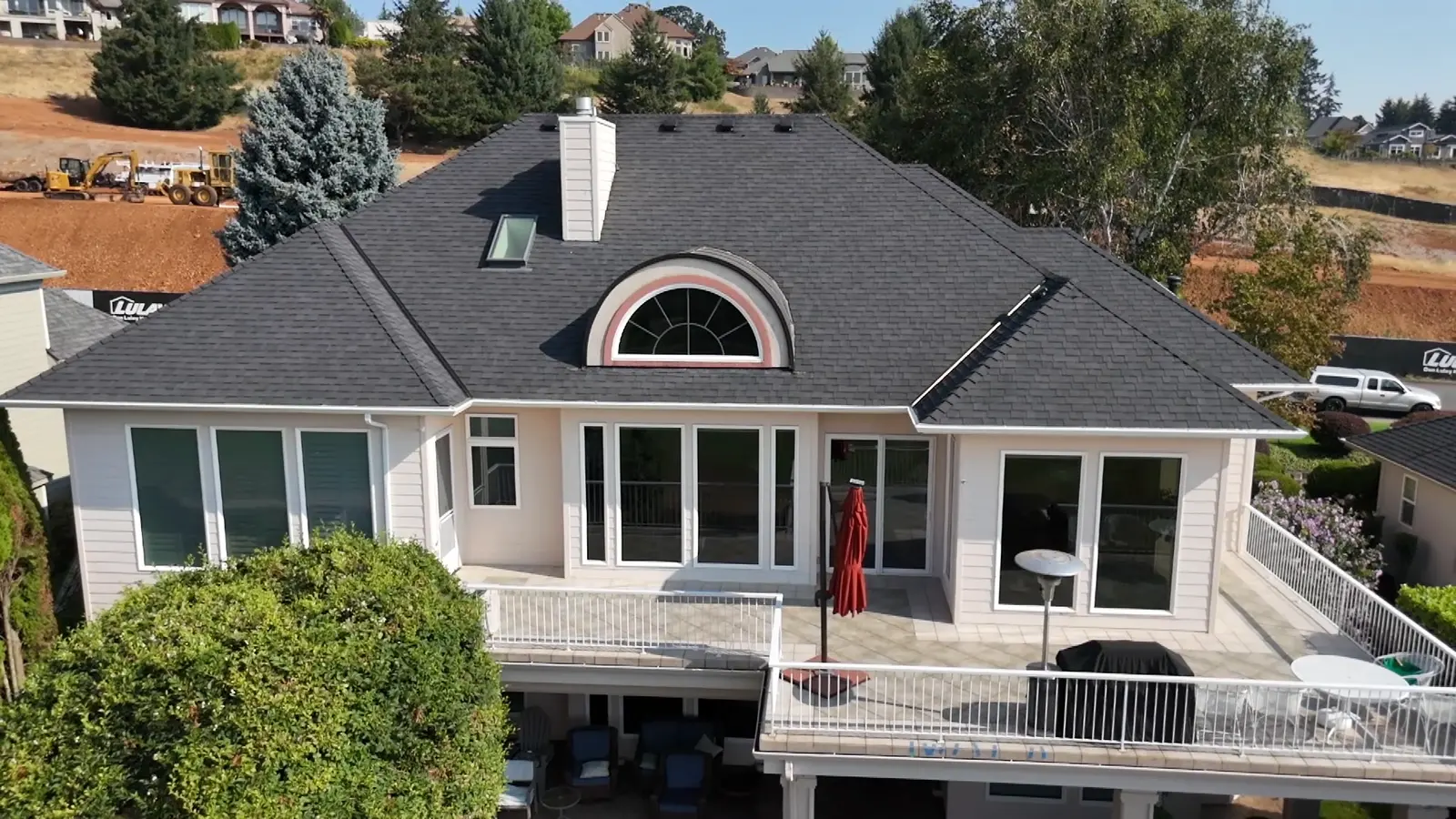 Rear of a two-story golf course home in white with burgundy trim before painting