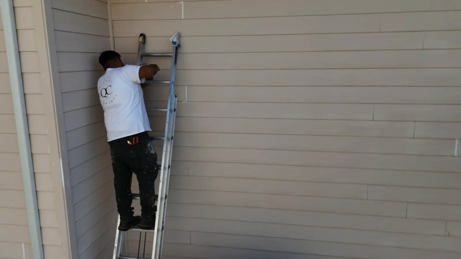 QC painter on a ladder prepping lap siding