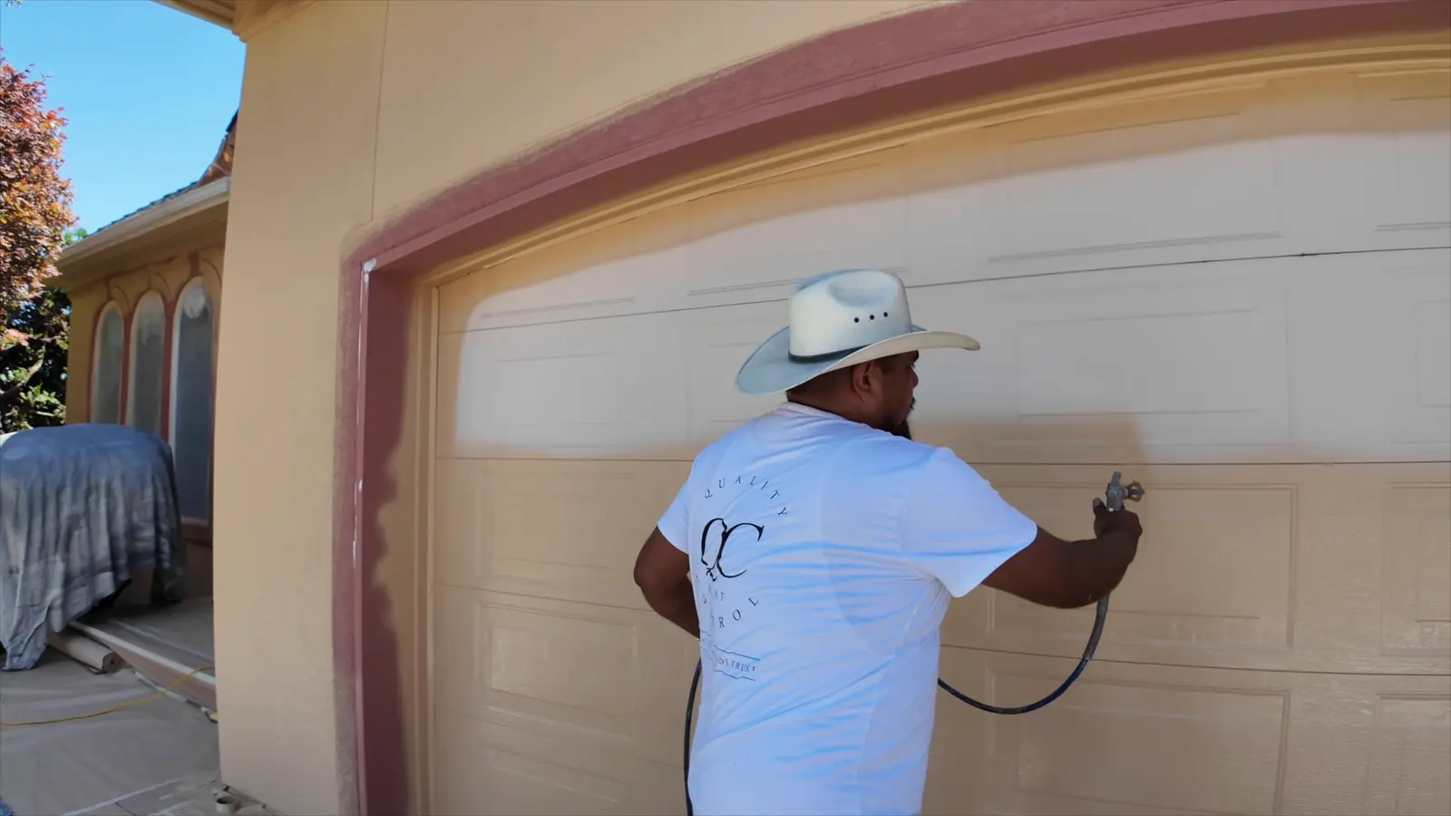 QC painter spraying a garage door on a golf course home