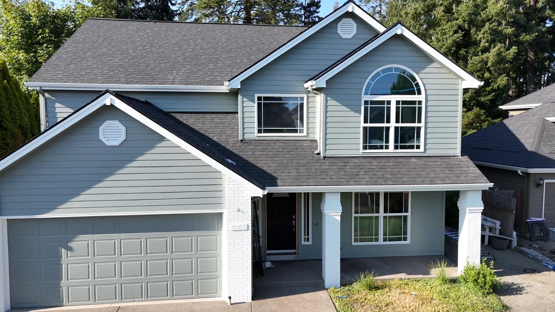 Two-story Keizer home after painting, sage green siding with white trim and an arched window