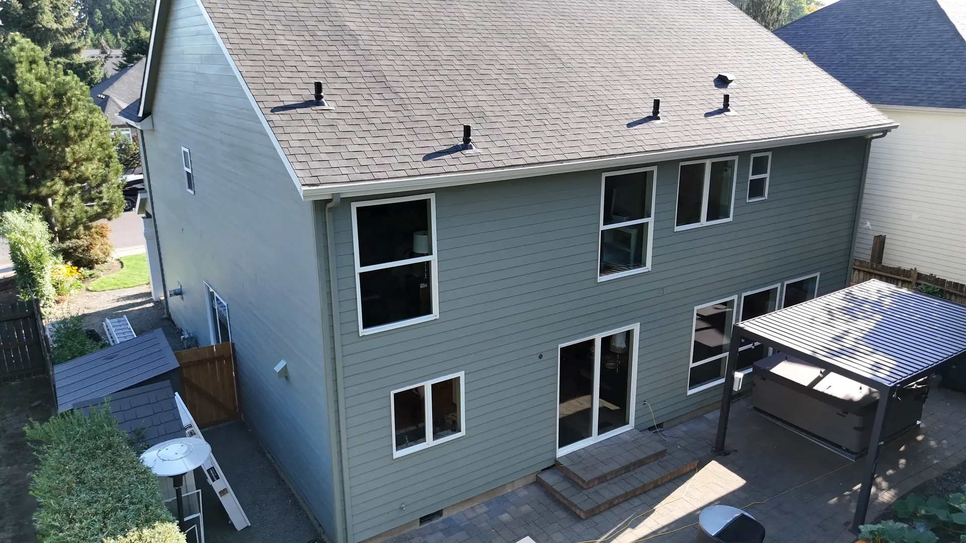 Back of the home, sage green siding with white window trim over the patio