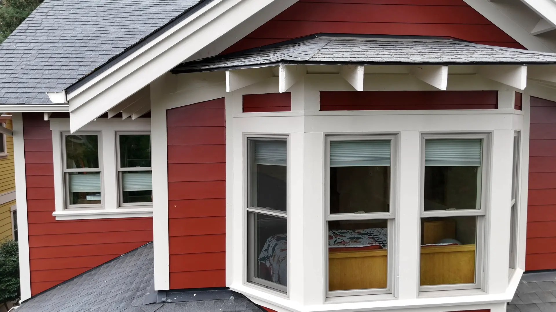 Close-up of the bay window with fresh white trim against red siding
