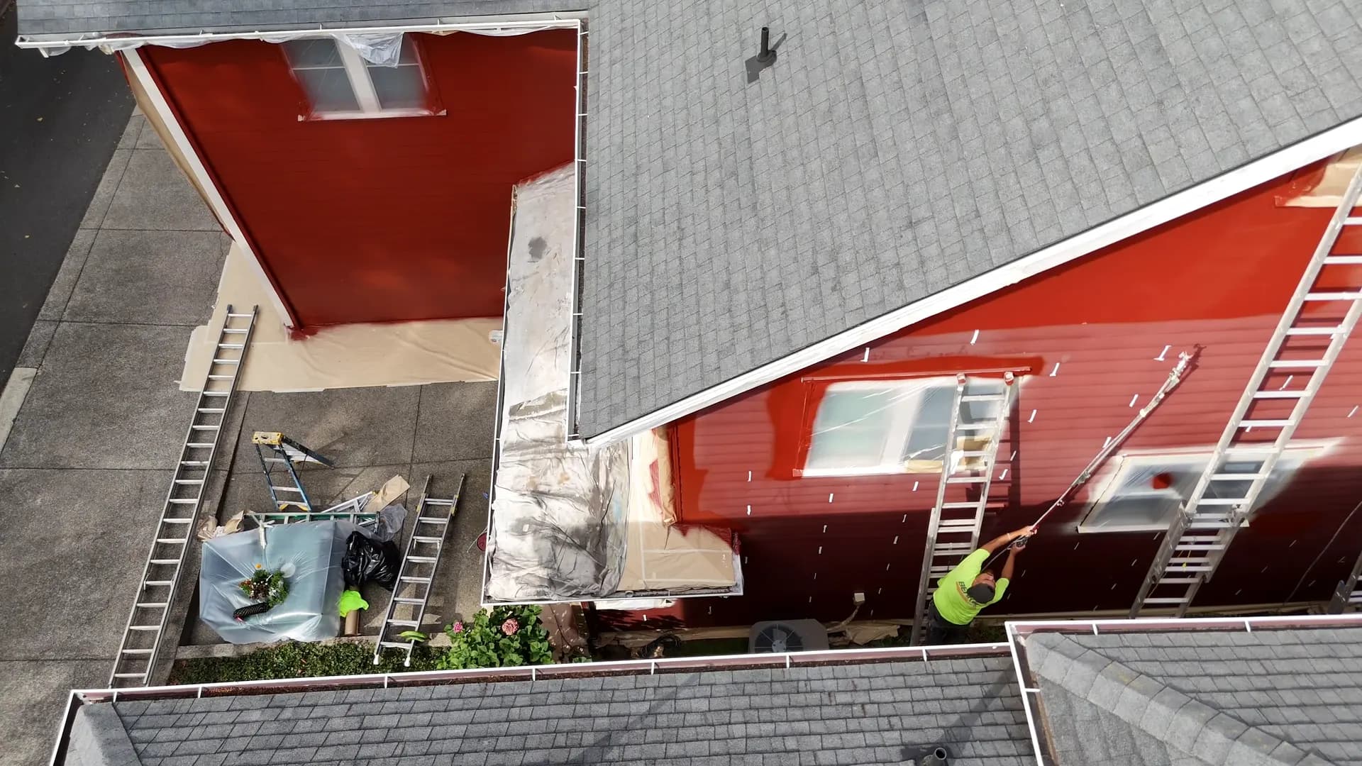 QC crew on ladders painting the red siding