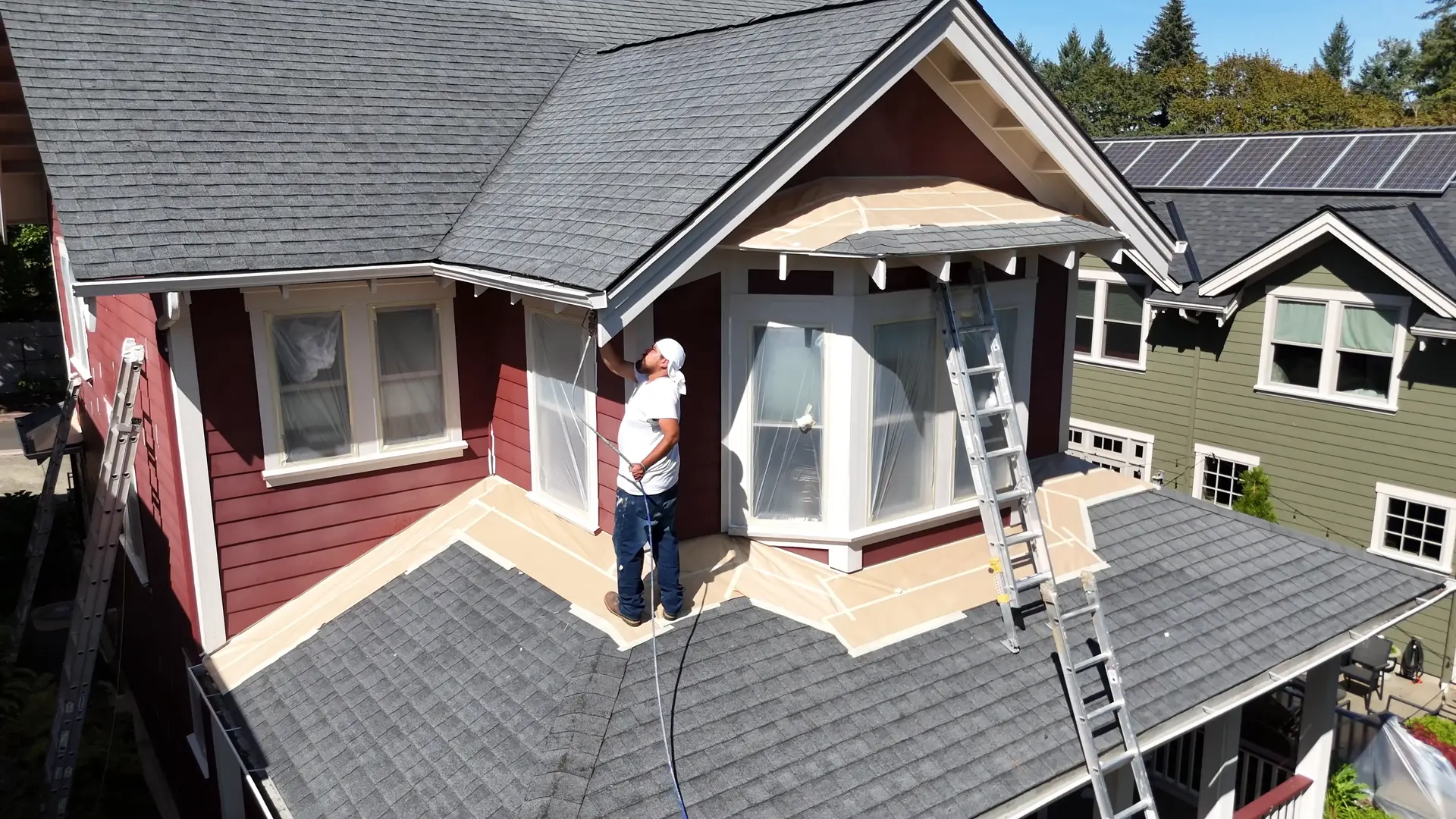 QC painter working on white trim around the bay window