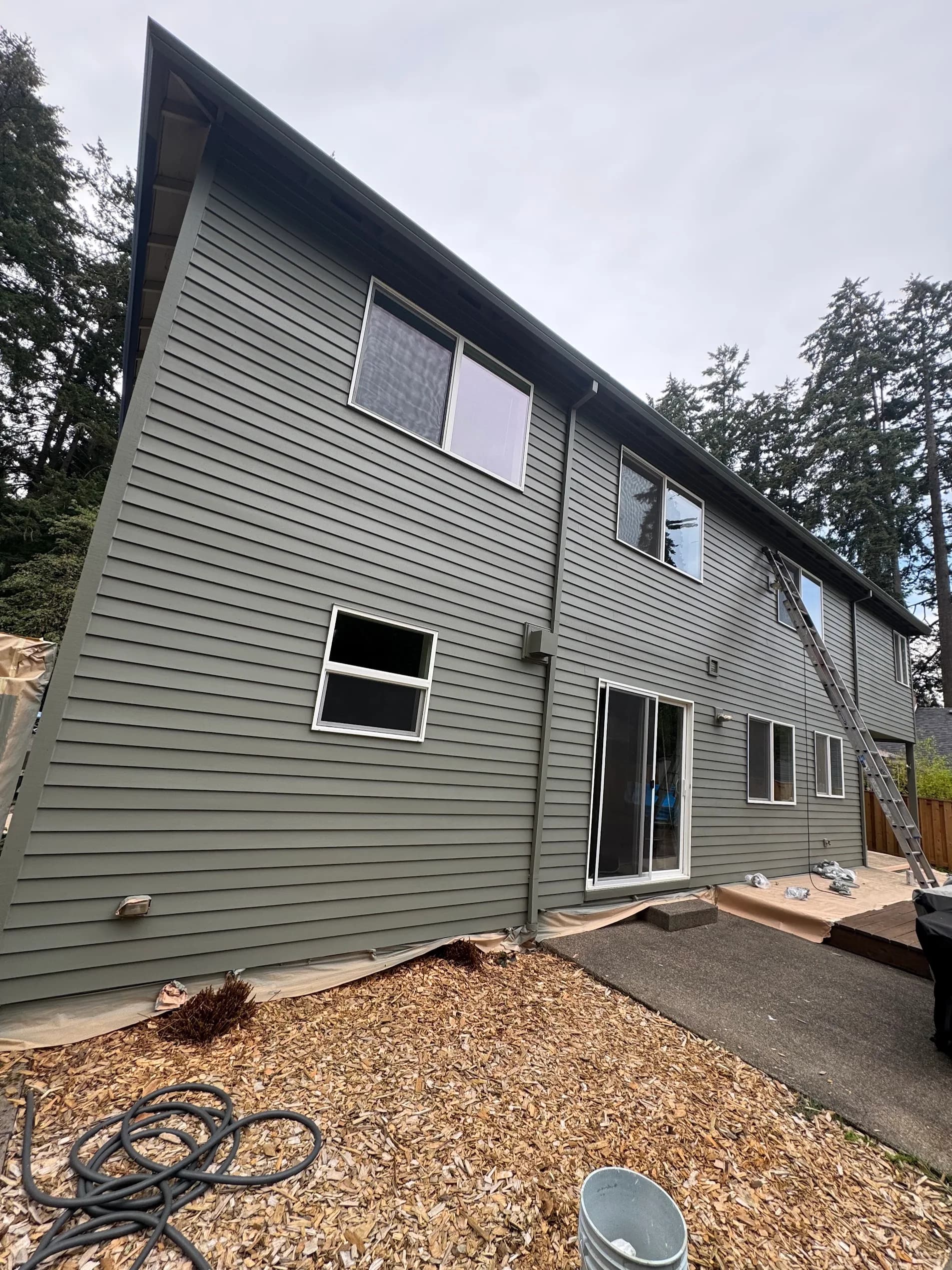 Two-story home exterior with new green siding paint and white window trim in Woodburn, Oregon