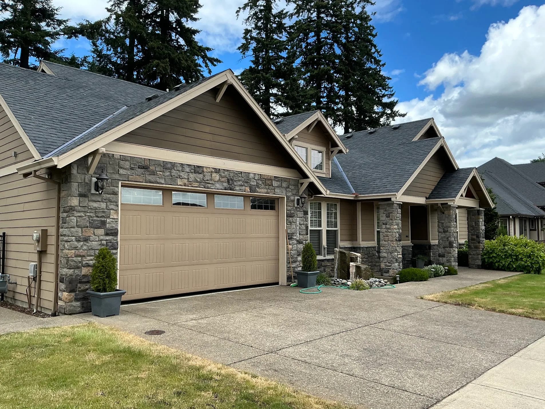 Craftsman home with warm tan siding, stone columns and repainted garage door before color change