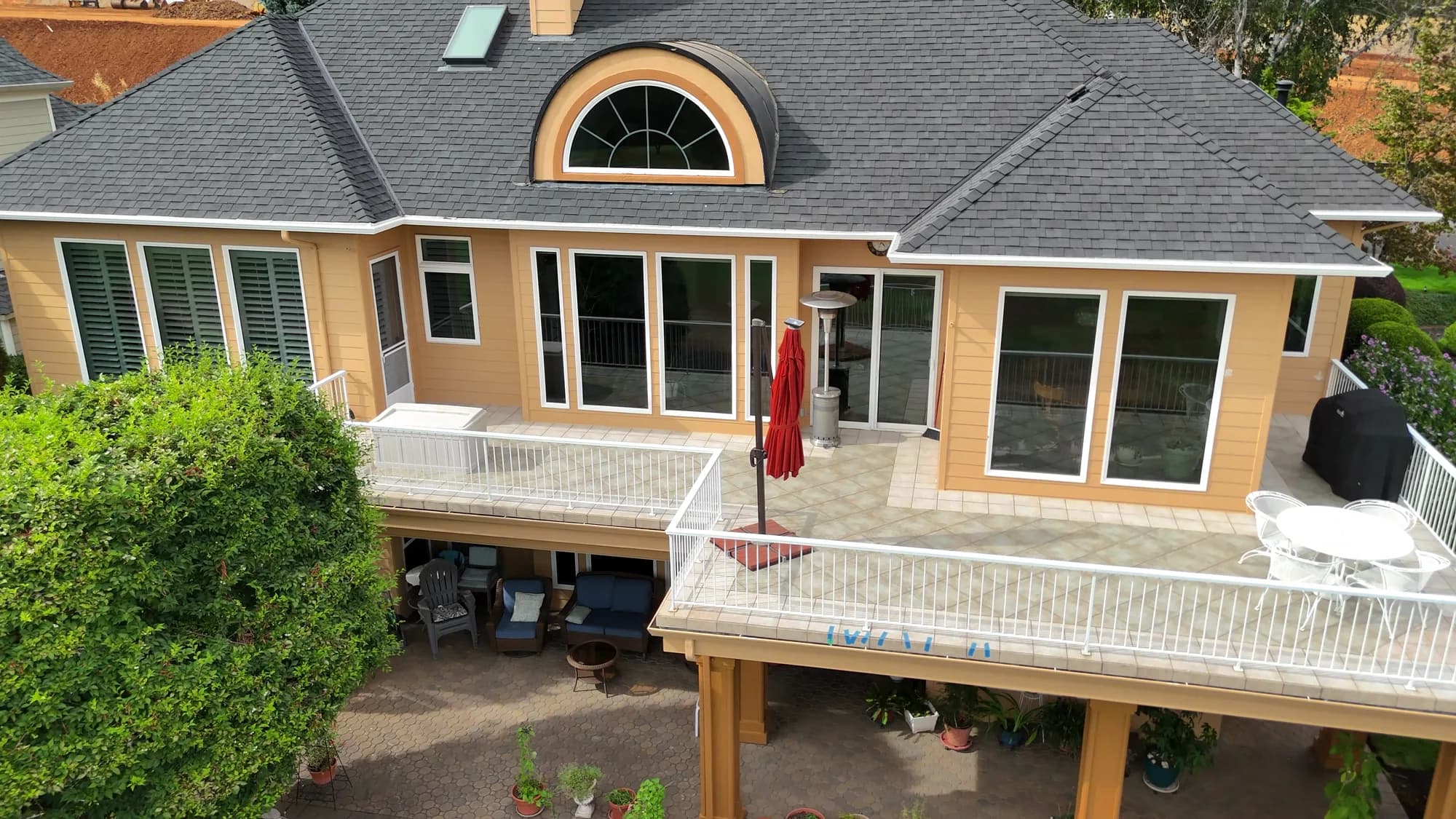 Rear elevation and multi-level deck of a luxury tan stucco home after full exterior repaint